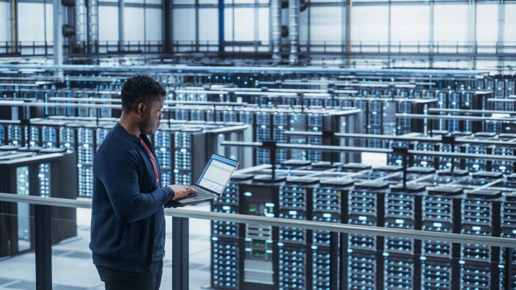 2 Hypergrowth AI Stocks to Buy and Hold for the Next Decade A technician overlooking a data center.
