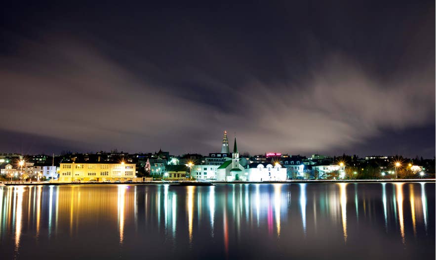 Reykjavik city skyline and lights reflecting on the water at night during May in Iceland.