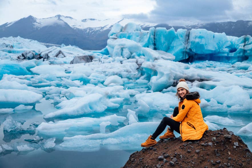 Woman dressed in warm layers at Jokulsarlon Glacier Lagoon, showing what to wear in Iceland near Vatnajokull.