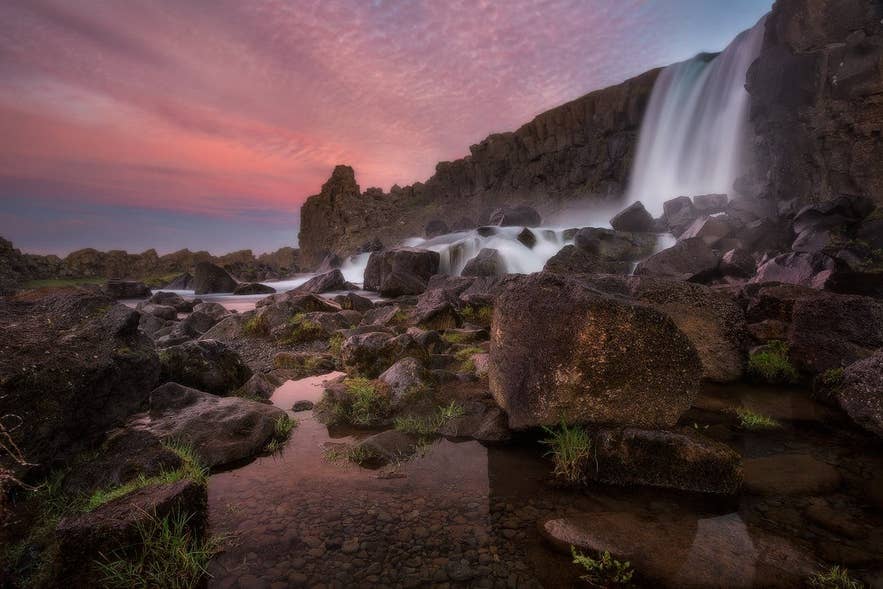 Waterfall at Thingvellir National Park at sunset, illustrating changing conditions that influence what to wear in Iceland. Waterfall at Thingvellir National Park at sunset, illustrating changing conditions that influence what to wear in Iceland.