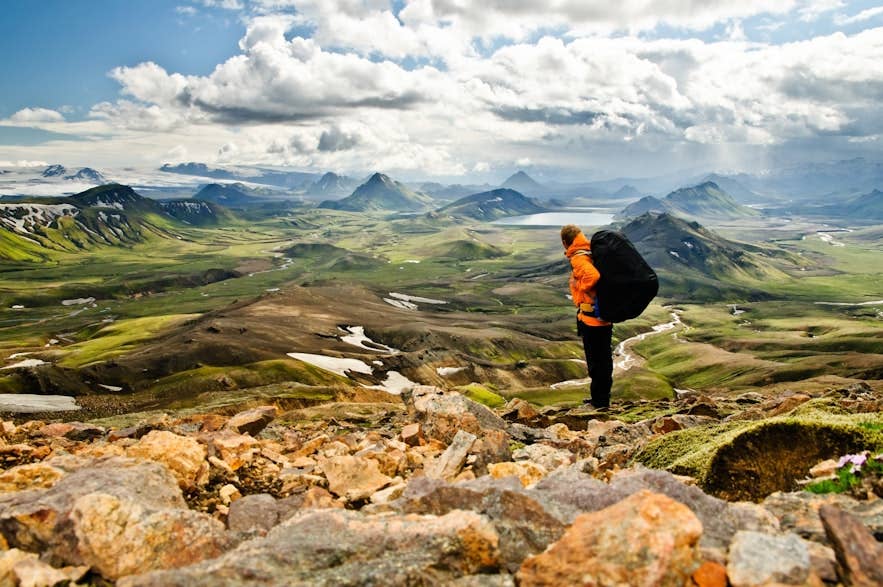 Hiker in Landmannalaugar shows what to wear in Iceland for summer trekking with layers, boots, and a weatherproof backpack. Hiker in Landmannalaugar shows what to wear in Iceland for summer trekking with layers, boots, and a weatherproof backpack.