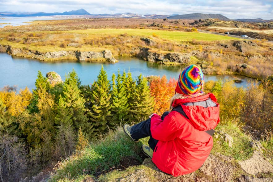 Woman in a red jacket overlooking Lake Myvatn in North Iceland, showing practical layers for what to wear in Iceland. Woman in a red jacket overlooking Lake Myvatn in North Iceland, showing practical layers for what to wear in Iceland.