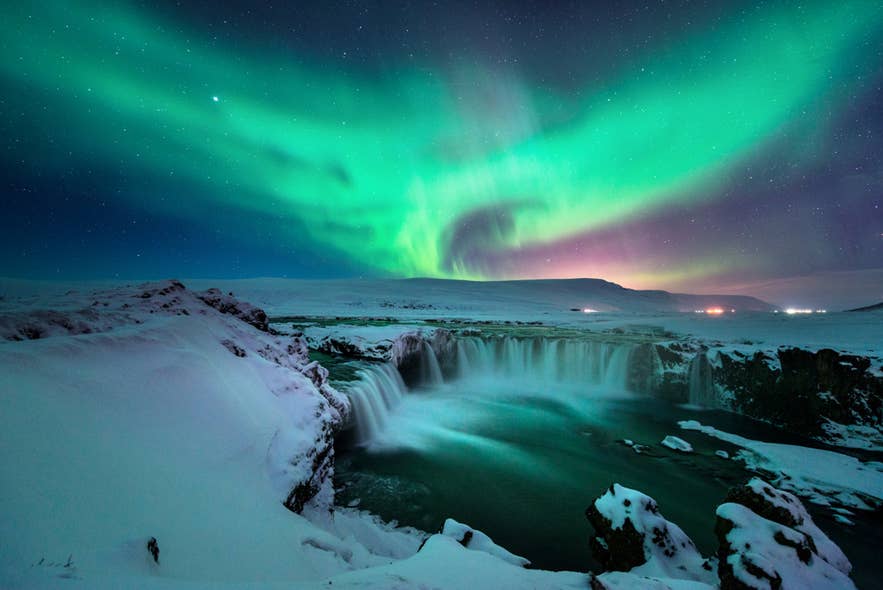 Northern lights over Godafoss in winter snow, where insulated boots and thermal layers are key for what to wear in Iceland. Northern lights over Godafoss in winter snow, where insulated boots and thermal layers are key for what to wear in Iceland.