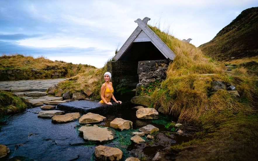 Traveler in a hot spring at Reykjadalur Valley shows what to wear in Iceland for geothermal bathing in natural pools. Traveler in a hot spring at Reykjadalur Valley shows what to wear in Iceland for geothermal bathing in natural pools.
