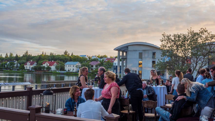 Locals and tourists in summer outfits at a Reykjavik bar show what to wear in Iceland for outdoor dining in warm weather. Locals and tourists in summer outfits at a Reykjavik bar show what to wear in Iceland for outdoor dining in warm weather.