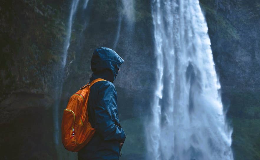 Traveler at Seljalandsfoss Waterfall showing what to wear in Iceland for rainy, windy days on the South Coast. Traveler at Seljalandsfoss Waterfall showing what to wear in Iceland for rainy, windy days on the South Coast.