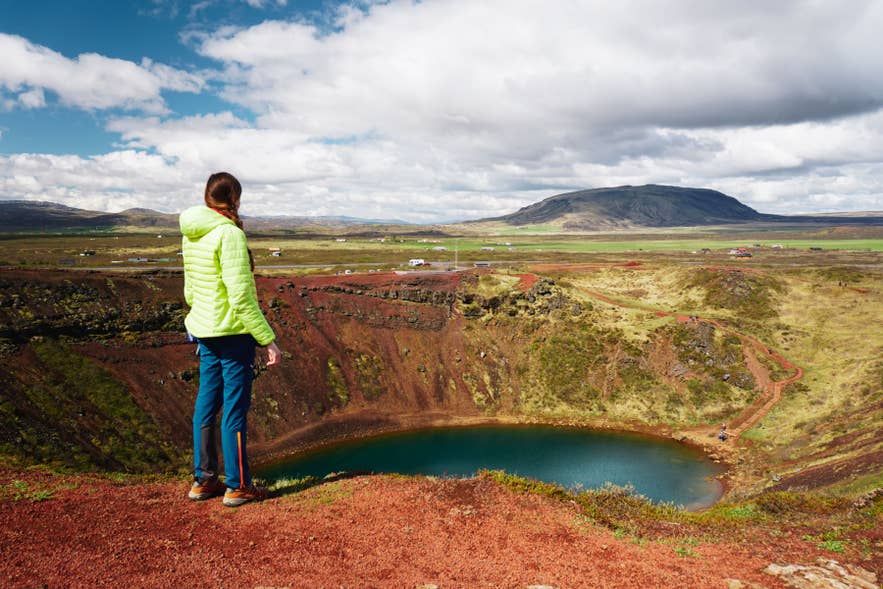Woman overlooking Kerid Crater near Selfoss in South Iceland, wearing outdoor layers that show what to wear in Iceland. Woman overlooking Kerid Crater near Selfoss in South Iceland, wearing outdoor layers that show what to wear in Iceland.