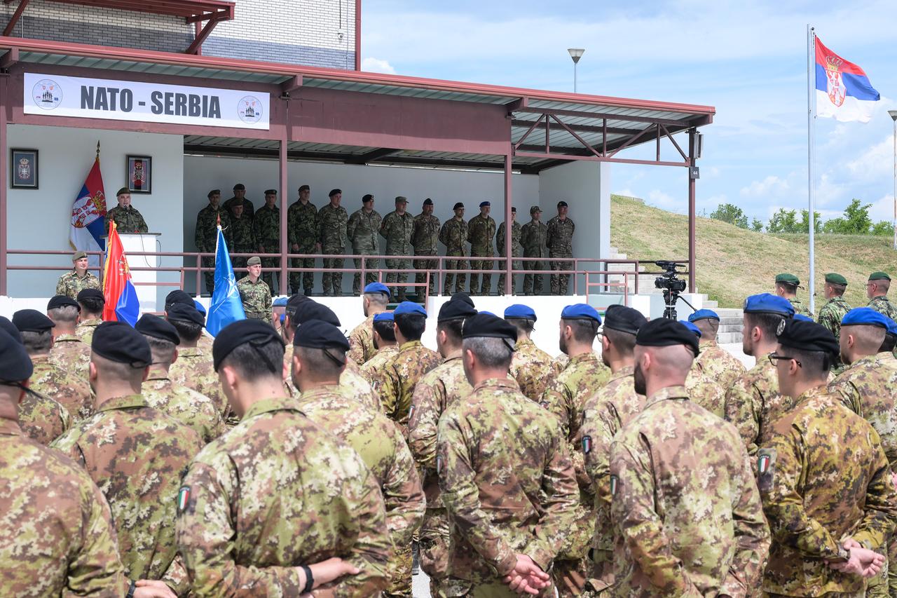 The photo shows Serbian and NATO soldiers standing side by side at a military training ground near Bujanovac in southern Serbia during the first-ever joint military exercise between Serbia and NATO forces. (Photo via Serbian Defense Ministry)