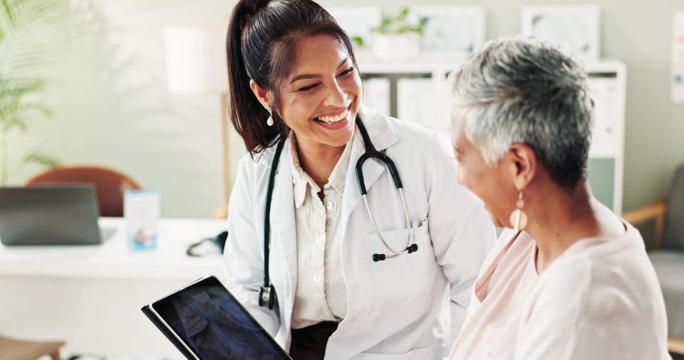 Mature woman, doctor and tablet for xray, support or conversation with cardiology checkup in office. Female person, medical professional and diagnosis talk for senior patient at clinic appointment