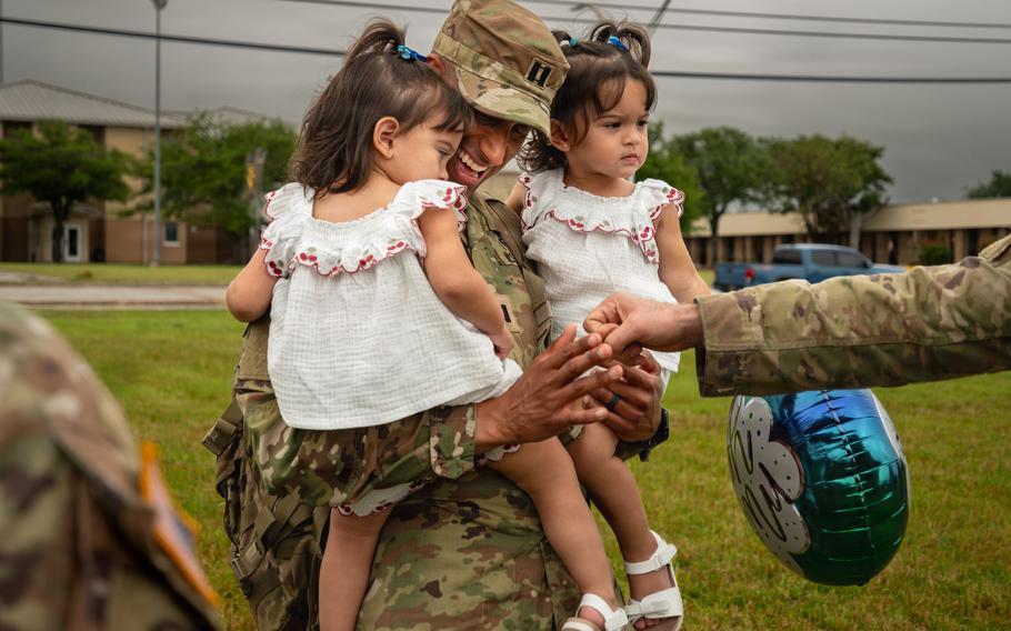 A soldier holds two toddlers.