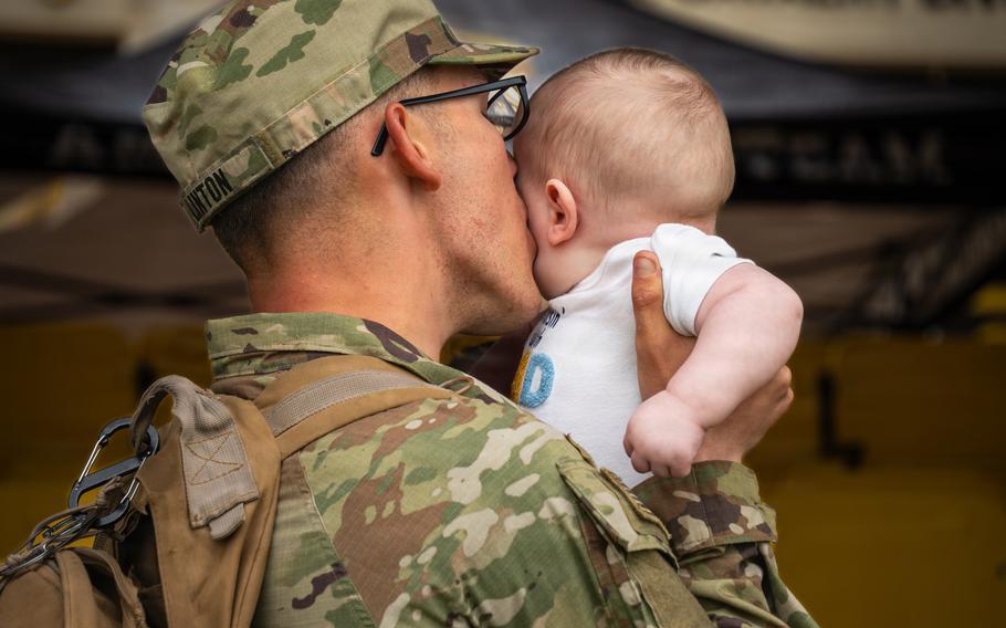 A soldier kisses a baby on the cheek.