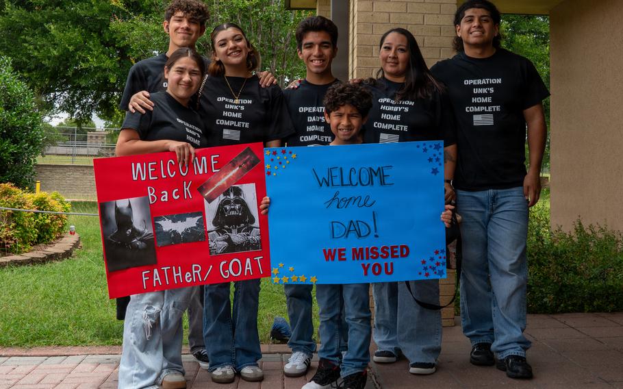 A family holding up “Welcome Home” signs.