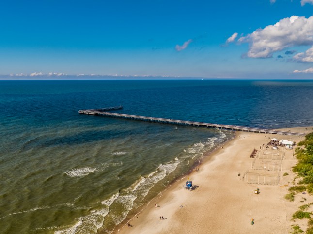 An aerial view of Palanga beach in Lithuania on a bright sunny day with a blue sky. The resort pier stretches out into the Baltic sea.