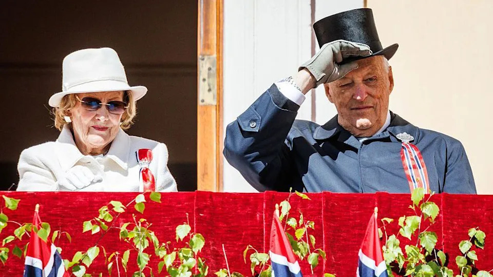 A man and woman on a platform in front of Norwegian flags