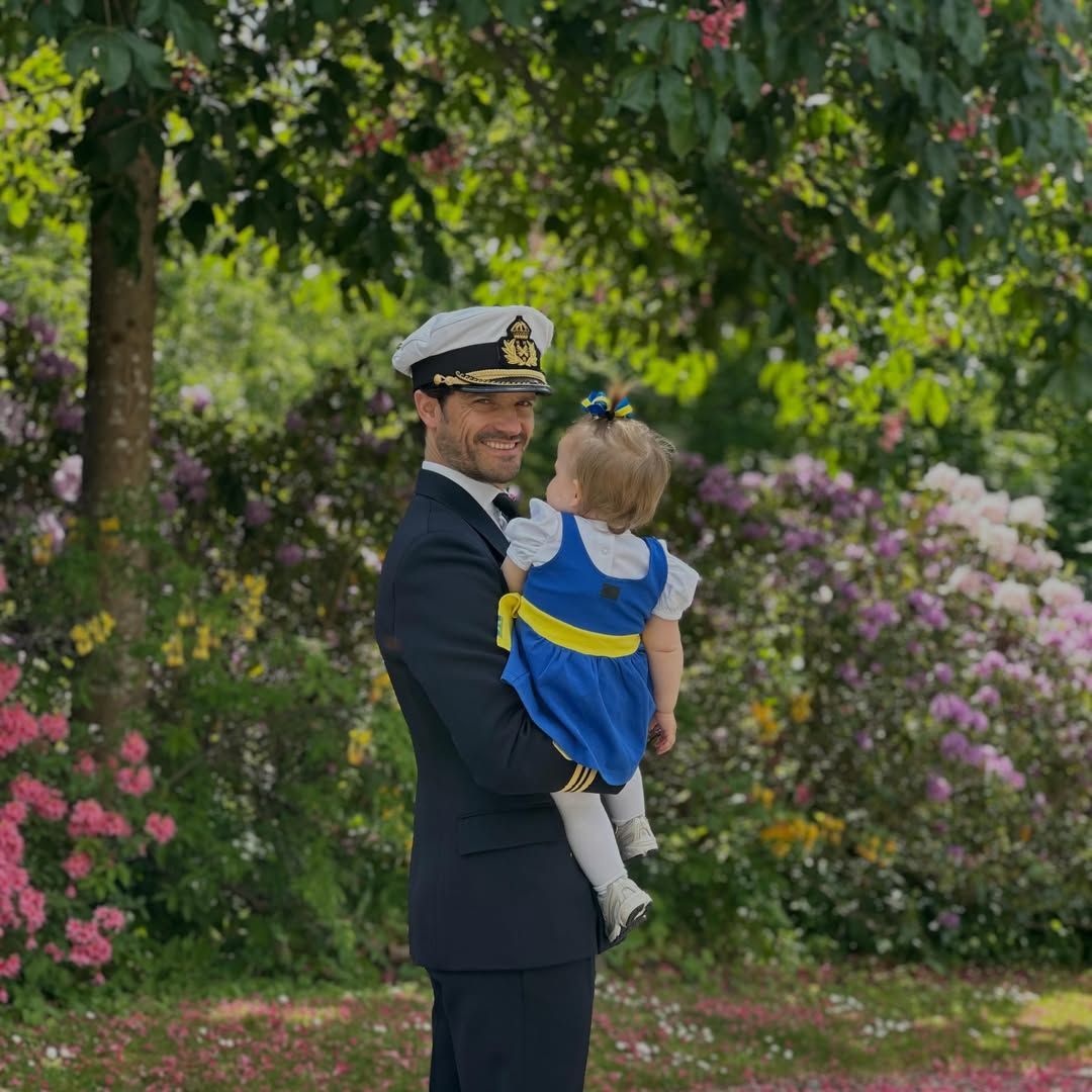 Princess Ines, dressed in traditional Swedish attire, steals the spotlight while being held by her father, Prince Carl Philip, during Sweden’s National Day celebrations.