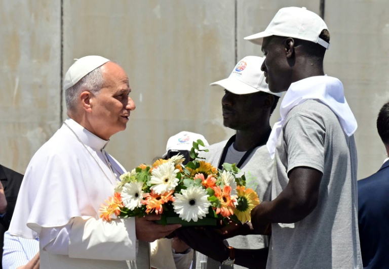 Pope Leo XIV is presented a wreath by two migrants, to make a floral tribute to remember all the migrants who perished during their journey, at the Port of Arguineguin on the Canary Island of Gran Canaria.