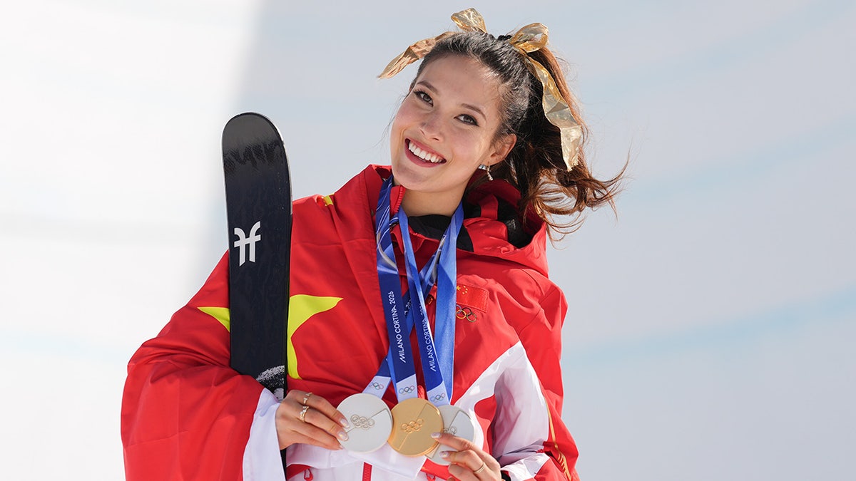 Eileen Gu smiling and posing with her medals after winning freestyle skiing halfpipe.