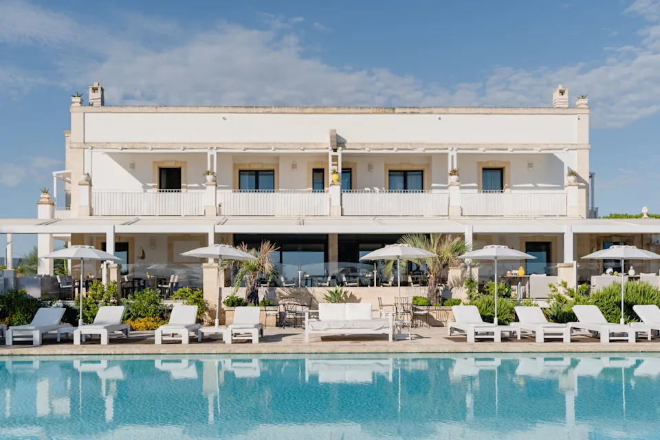 Exterior view of Canne Bianche Lifestyle Hotel in Puglia with whitewashed walls and palm-lined grounds