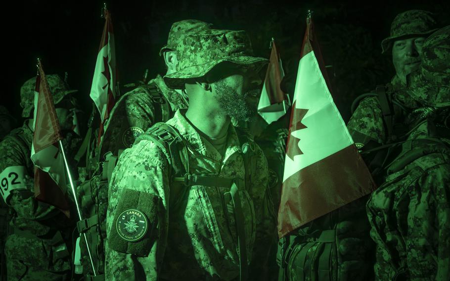 A night-vision photo of a uniformed Canadian soldier standing among his peers.