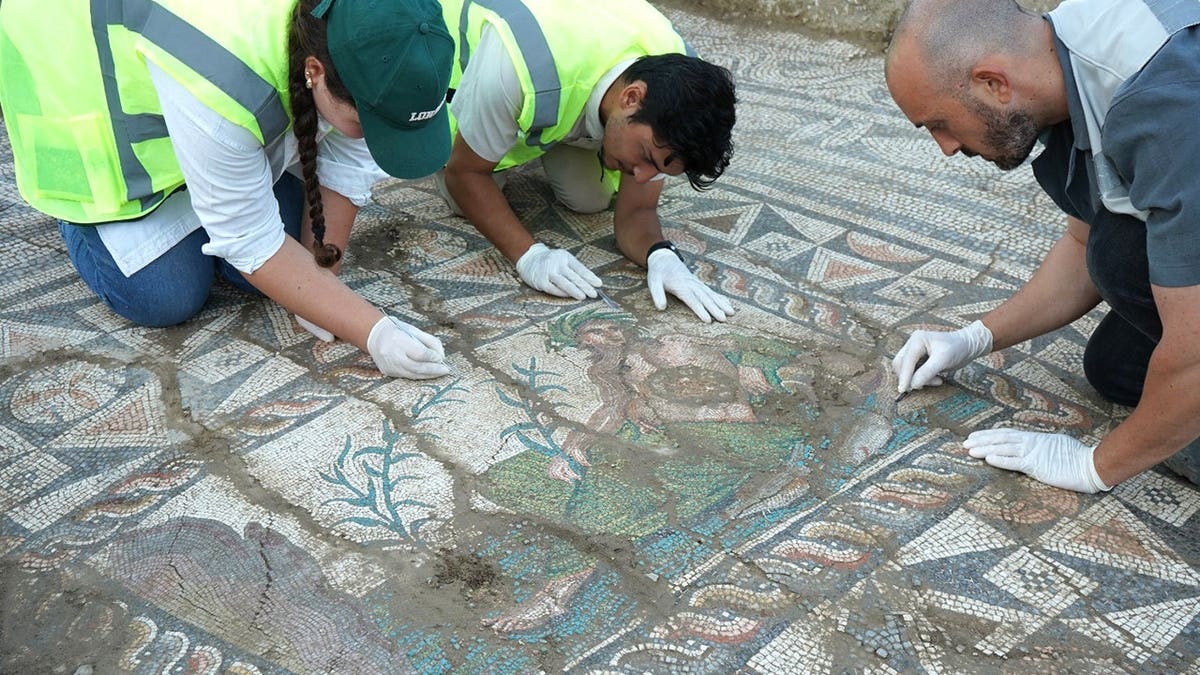 Archaeologists brushing dirt away from mosaic