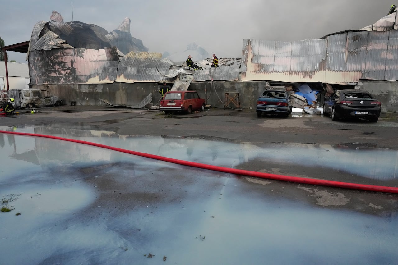Firefighters put out a fire at a large warehouse. In the foreground spilled milk is shown on the ground.