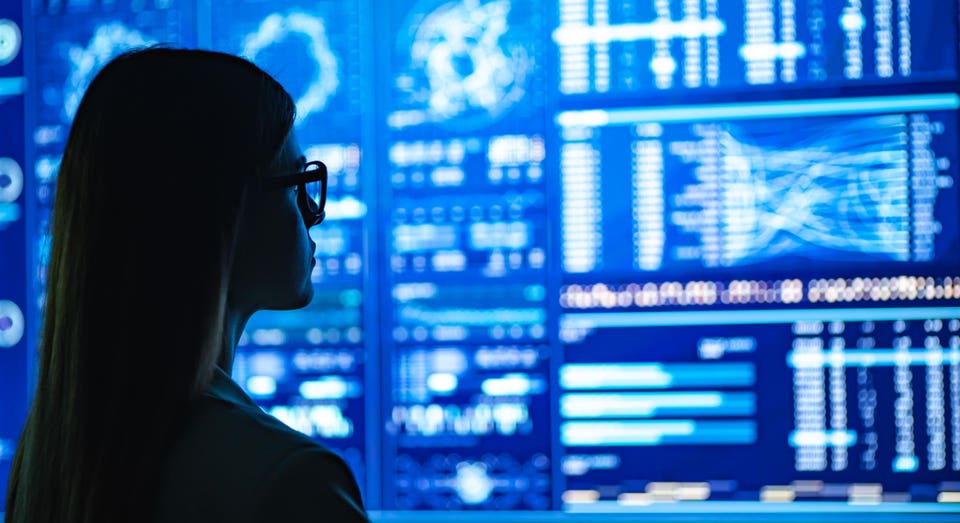 The businesswoman standing near the blue display