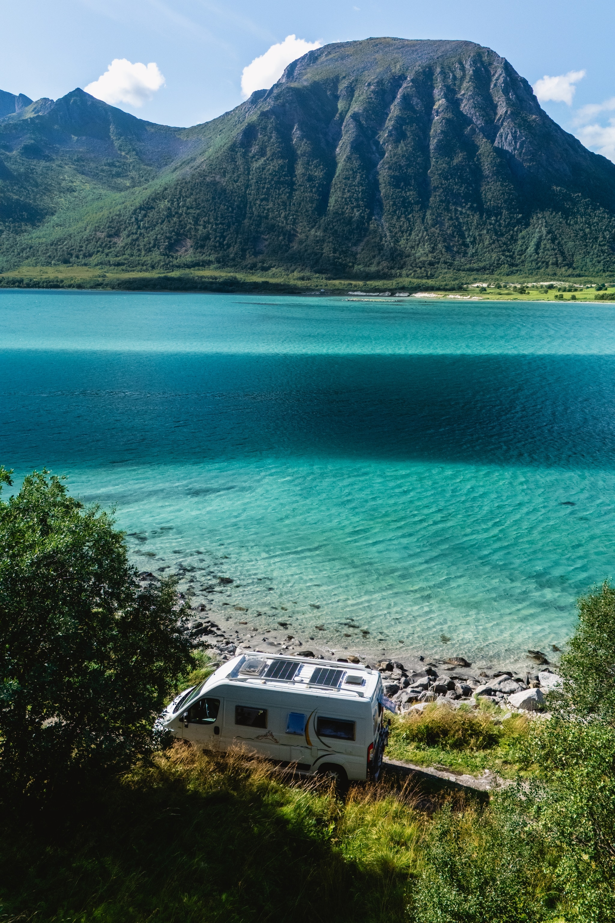 Camper van by blue waters and mountain skyline