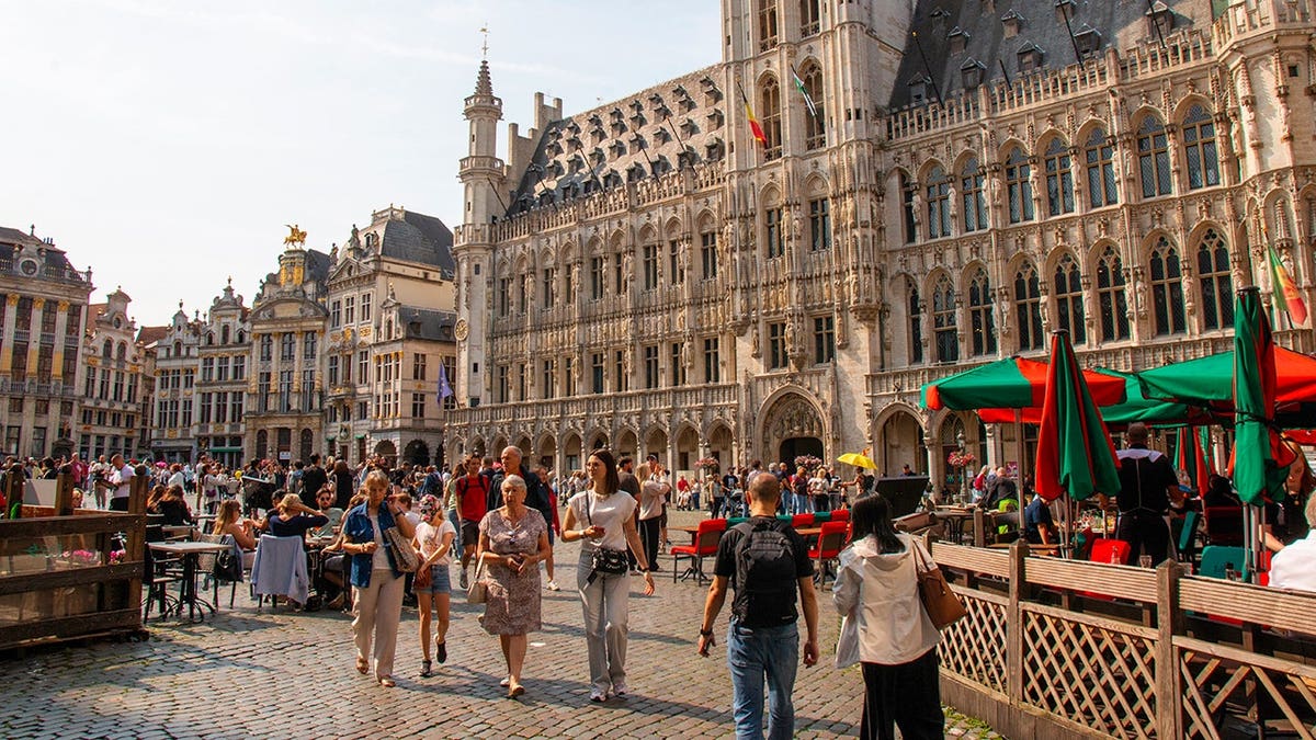 Crowds explore shops and dine outdoors on a vibrant day in Brussels.