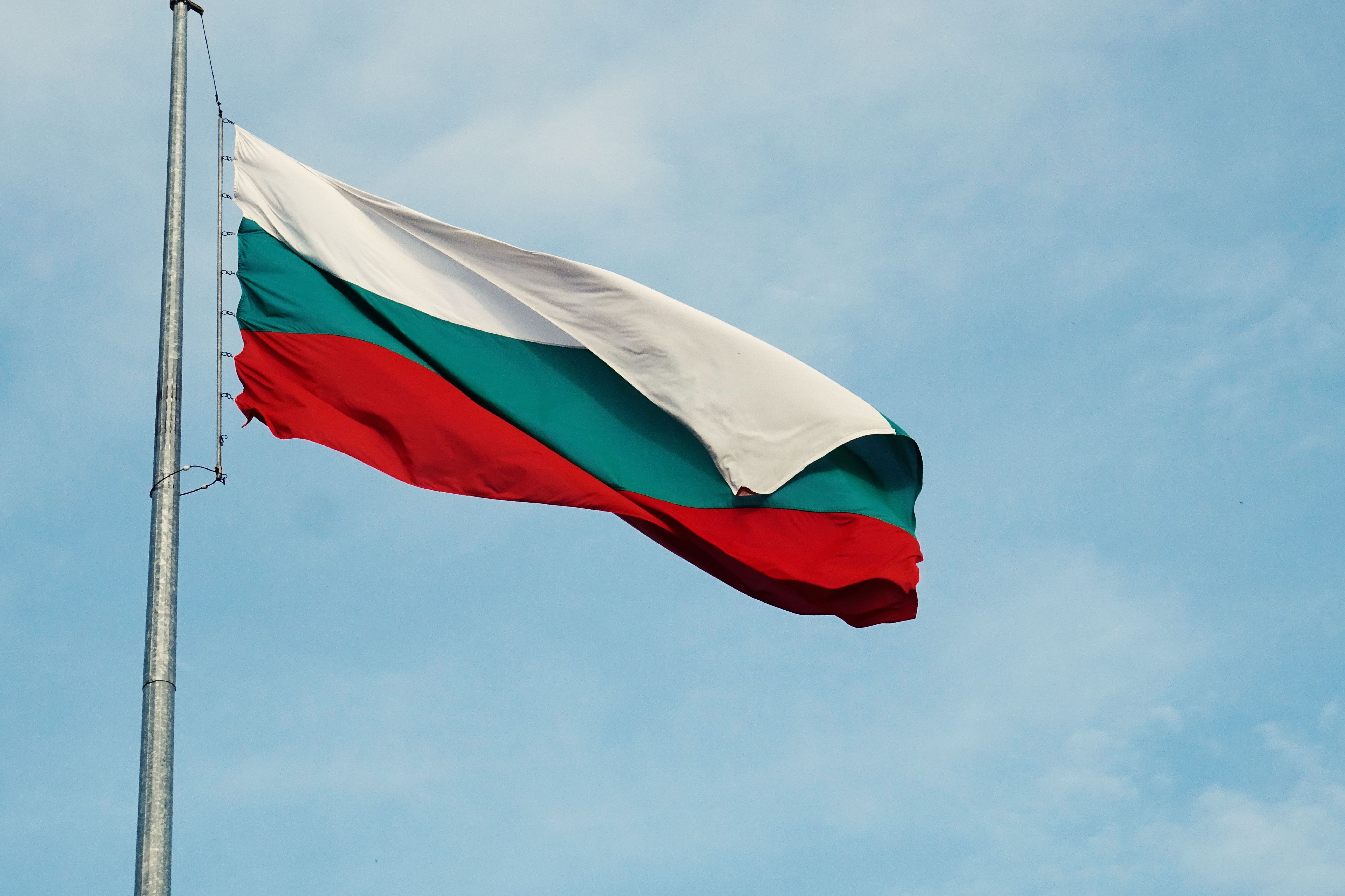 Bulgarian flag waving on a flagpole against a blue sky