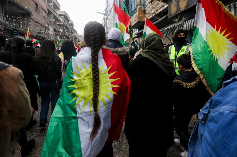 A person wrapped in a Kurdish flag takes part in a demonstration of Syrian Kurds, to demand their rights in the Syrian constitution and in support of Kurdish unity, in Qamishli, Syria on February 1, 2026