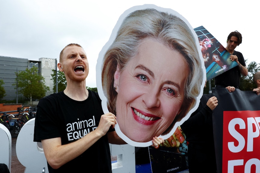An animal rights demonstrator holds a cutout of the face of European Commission President Ursula von der Leyen.