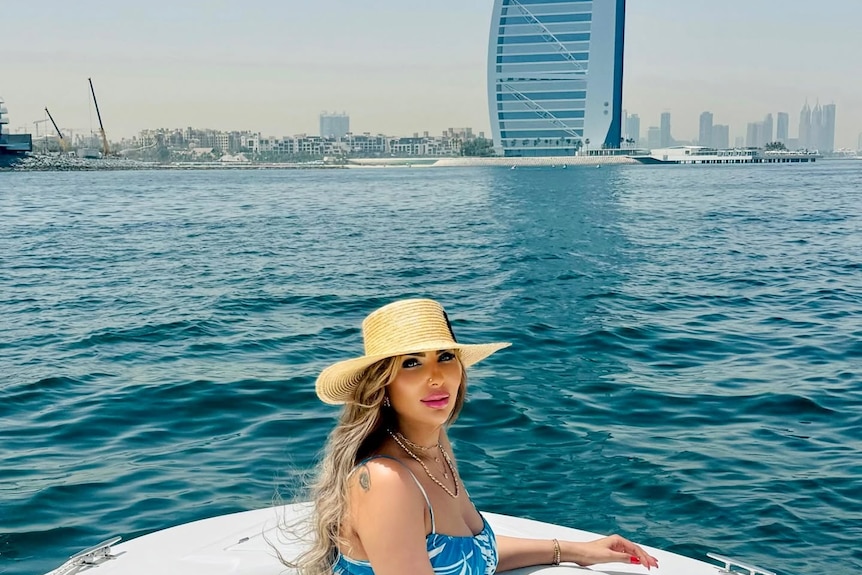 A 40-year-old woman with heavy make-up smiles at camera on small boat in Dubai.