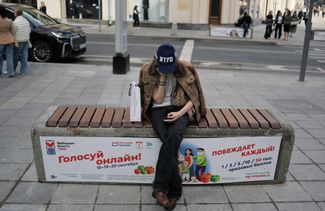 A young woman sits on a bench holding a poster urging people to vote online in the State Duma election. September 9, 2026
