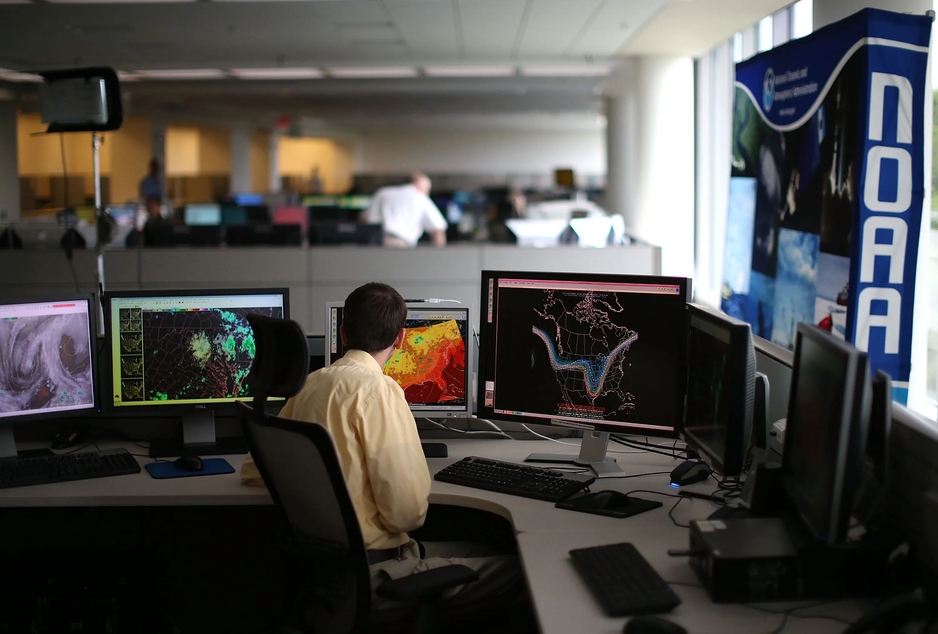 A man looks at multiple screens showing science readings at NOAA