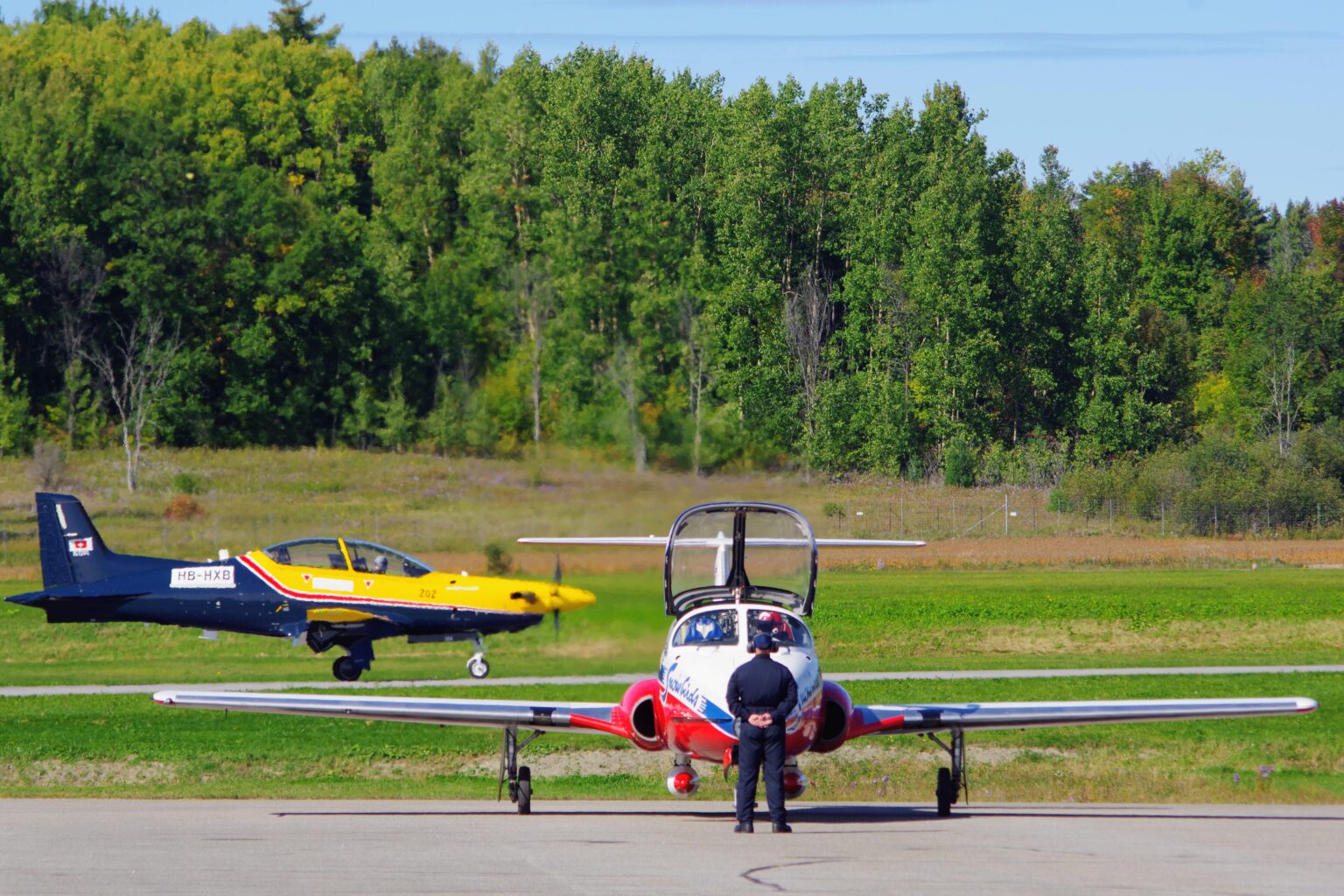 Goodbye, CT-114 Tutor. Snowbirds prepare for their last Canadian show in the original aircraft, as the Pilatus PC-21 replacing the Tutor taxies in the background.