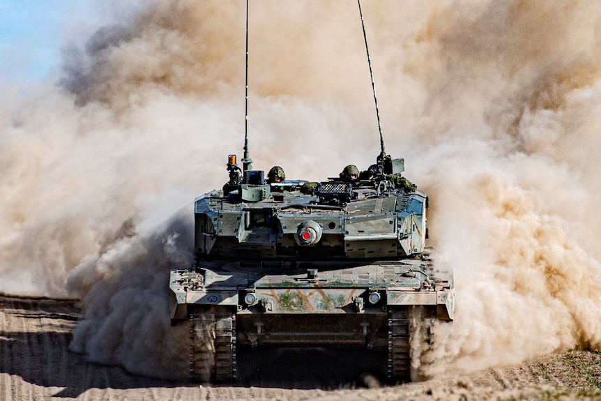 A Leopard 2A4 tank kicking up dust as it drives at Wainwright.