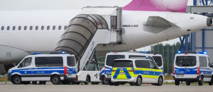 German police vehicles are parked beside a passenger aircraft at an airport during the deportation of Afghan migrants from Germany (Photo: Hendrik Schmidt/dpa/picture alliance)