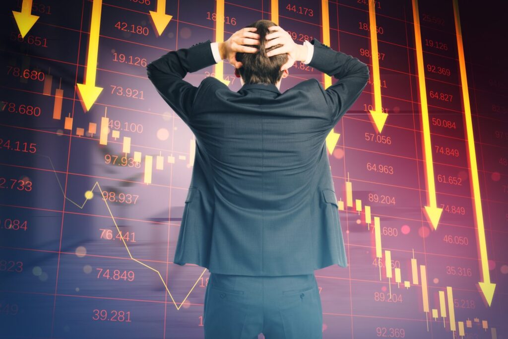 The Nasdaq 100 Briefly Fell Into a Correction as the AI Trade Cracks A person in a dark suit stands with their back to the viewer, hands clasped behind their head, looking at a digital stock chart. The chart features a dark purple background with a grid pattern, displaying numerous red financial figures and yellow downward arrows indicating a market decline. Yellow candlestick-like bars and a light yellow line graph also show a downtrend.